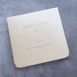 Detailed view of the beige ticket storage album with vintage metal corners and fabric cover.