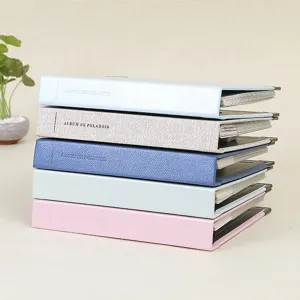 Detail view of colorful leather 3 inch polaroid photo albums stacked neatly with metal corners.