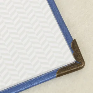 Close-up detail of 3-inch leather photo album with vintage bronze metal corner and chevron insert.