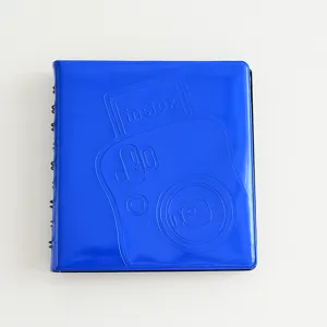 Close-up detail of a blue mini photo album cover with spiral binding and embossed camera design.