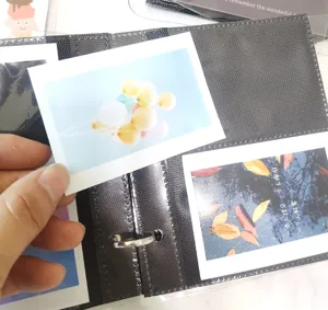 Detail shot of loose-leaf PP photo album interior page with insert card and metal ring binder.
