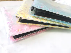 Transparent loose-leaf photo album detail showing glitter sequin cover and black inner pages.