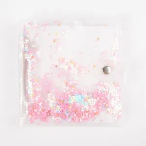 Close-up detail of a transparent PVC loose-leaf photo album with shiny pink glitter sparkles.