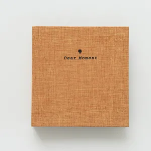 Detailed close-up shot of the orange linen photo album cover with minimalist text design.