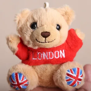 Plush teddy bear souvenir wearing red hoodie with London embroidery and UK flag feet design.