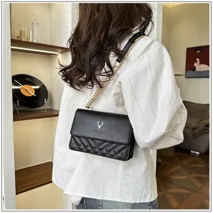 Detail view of the black quilted shoulder bag showing chain strap and elegant metallic deer logo.