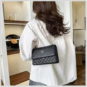 Detailed shot of a stylish black quilted shoulder bag with gold chain strap and elegant deer logo.