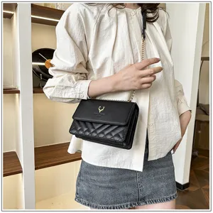 Close-up detail of stylish black quilted chain shoulder bag with elegant gold deer logo hardware.