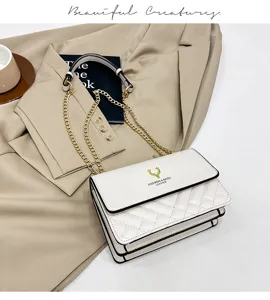 Detail view of white quilted shoulder bag, featuring gold chain and flap design, chic and stylish.