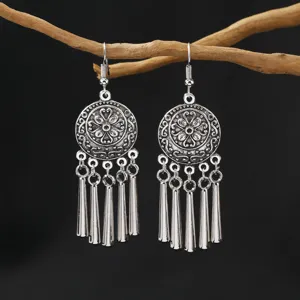 Detailed close-up shot of vintage ethnic silver tassel dangle earrings on rustic wooden prop.