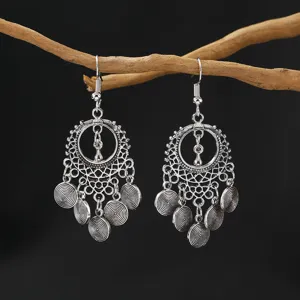 Close-up detail of vintage silver bohemian boho long tassel dangle earrings hanging on a branch.