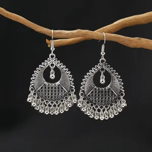 Close-up detail of ethnic vintage silver drop earrings with delicate cutout and tassel beads.