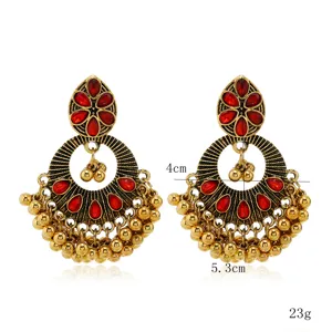 Close-up detail of ethnic red stone vintage gold jhumka earrings with hanging bead tassels.