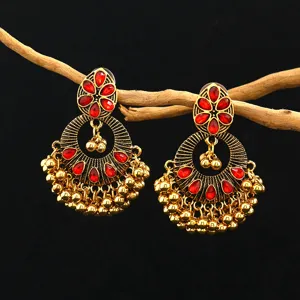 Close-up detail of vintage Indian ethnic red crystal gold drop earrings with delicate bead tassels.