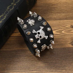 Bracelet manchette en cuir noir style rock punk avec rivets métalliques et têtes de mort argentées.