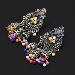 Close-up of vintage bohemian ethnic style drop earrings with colorful enamel and bead tassels.