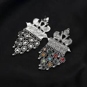 Close-up detail of vintage bohemian ethnic peacock metal drop earrings with colorful beads.