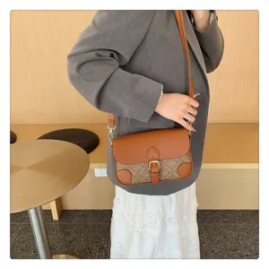 Detailed shot of retro contrast color shoulder bag, showing leather flap and monogram print.