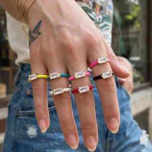 Close-up detail shot of colorful enamel baguette cubic zirconia rings, vibrant stackable design.