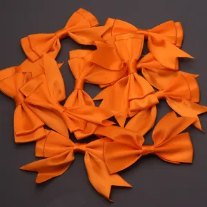 Close-up detail of vibrant orange satin swallowtail ribbon bows, perfect for gift packaging and DIY crafts.