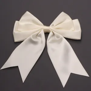 Detailed view of the cream satin double-tail bow accessory, featuring smooth glossy texture.