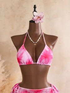 Detail du haut de bikini halter tie-dye rose avec collier de coquillage et fleur.