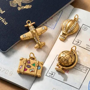 Vue détaillée des pendentifs de voyage en acier inoxydable plaqué or avec globe et avion.