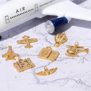 Gros plan détaillé de pendentifs dorés sur le thème du voyage avec avion et passeport pour bijoux.