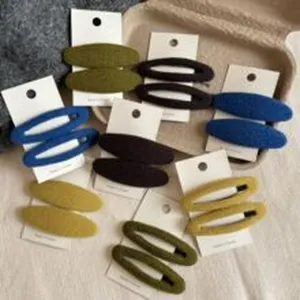 Detailed view of colorful oval hair clips wrapped in soft felt, simple and vintage design.
