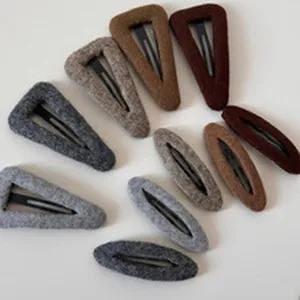 Close-up detail of soft fuzzy triangle and oval hair clips in various neutral autumn colors.