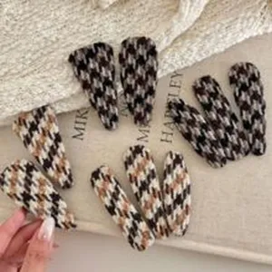Detailed view of vintage houndstooth hair clips, stylish and versatile fabric snap clips for daily styling.