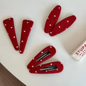 Red velvet hair clip detail view showing cute white heart patterns, perfect for daily styling.