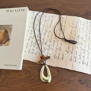 Lunga collana vintage in legno con ciondolo geometrico dorato e cordino marrone da maglione.