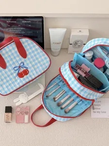 Detailed view of blue gingham makeup bag with cherry embroidery, multi-layer travel cosmetic storage.