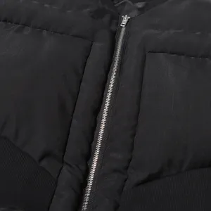 Close-up detail of black winter puffer jacket, featuring metal zipper and quilted texture.