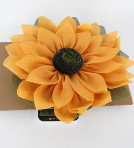 Close-up detail of fabric sunflower wreath element, showing yellow mesh petals and dark center.