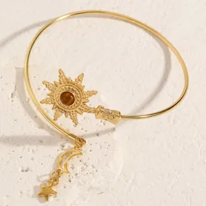 Vista di dettaglio del bracciale rigido sole in metallo dorato con ciondoli luna stella e pietra.