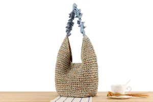 Gros plan du sac porté épaule tressé avec poignée à volants bleus et style estival.