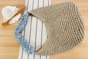 Détail du sac à épaule tressé, sac en paille avec bandoulière à volants bleus, style de plage.
