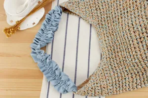 Vue detaillee du sac bandouliere en paille tressee avec sangle froncee bleue style vacances.