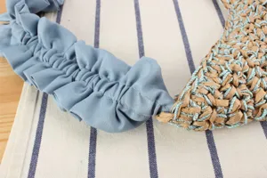 Vue détaillée d'un sac à épaule tressé élégant avec sangle plissée bleue.
