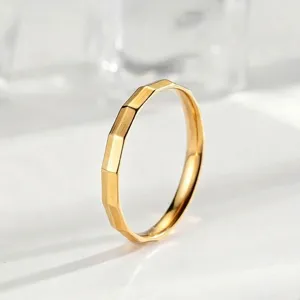Anillo de acero de titanio facetado dorado, detalle, diseño geométrico minimalista chic.