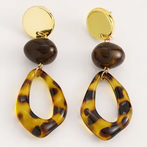 Detailed shot of trendy European American tortoiseshell and gold statement earrings for women.