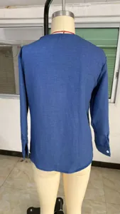 Detaillierte Ansicht der blauen Langarmbluse hinten, Stoffstruktur und Knopf am Manschettenärmel.