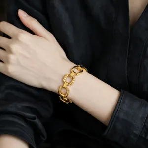 Close-up detail shot of a chunky gold geometric chain bracelet worn on wrist, stylish accessory.