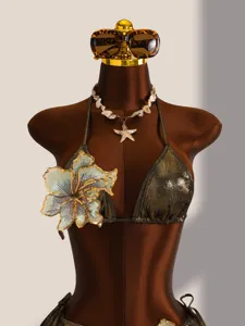 Detailopname van metalen bikini met grote bloemenborduursel en schelpenketting ornament.