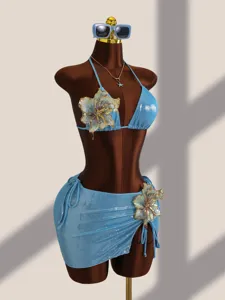 Detail van de blauwe glanzende 3-delige bikini met prachtige geborduurde bloemen op paspop.