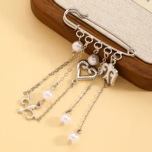 Close-up detail of exquisite ethnic style metal brooch with hanging chains and pearls.
