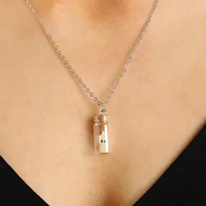 Gros plan detaille du pendentif collier bouteille fantome lumineuse sur le cou.