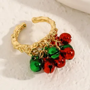 Gros plan détaillé d'une bague ouverte dorée avec de charmantes clochettes rouges et vertes.